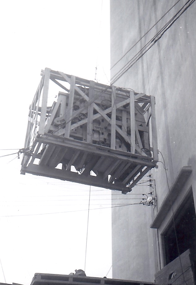 In this 1950 photo from Neil Lieb's archive, he explains what we see inside a crate that's being hoisted to the top of the Alta, Iowa, grain elevator. "That’s the motor for the belt and probably the gearbox," he says. "We didn’t take it out of the crate till we got it on top because the crate was designed so we could lift it. That little crane could hold a lot of weight. 